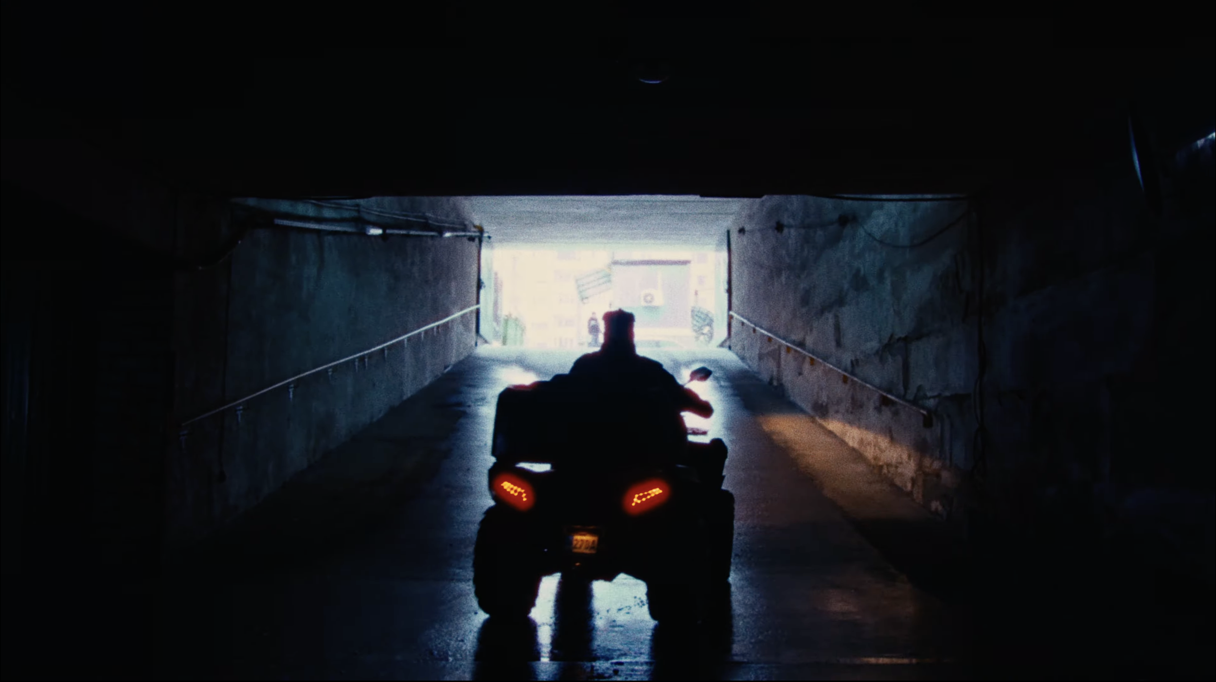 Motorcycle entering a dark tunnel with bright light at the end.