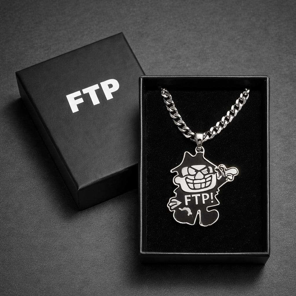 A silver necklace with a cartoonish character pendant inside a black jewelry box labeled 'FTP' next to its lid on a gray surface.