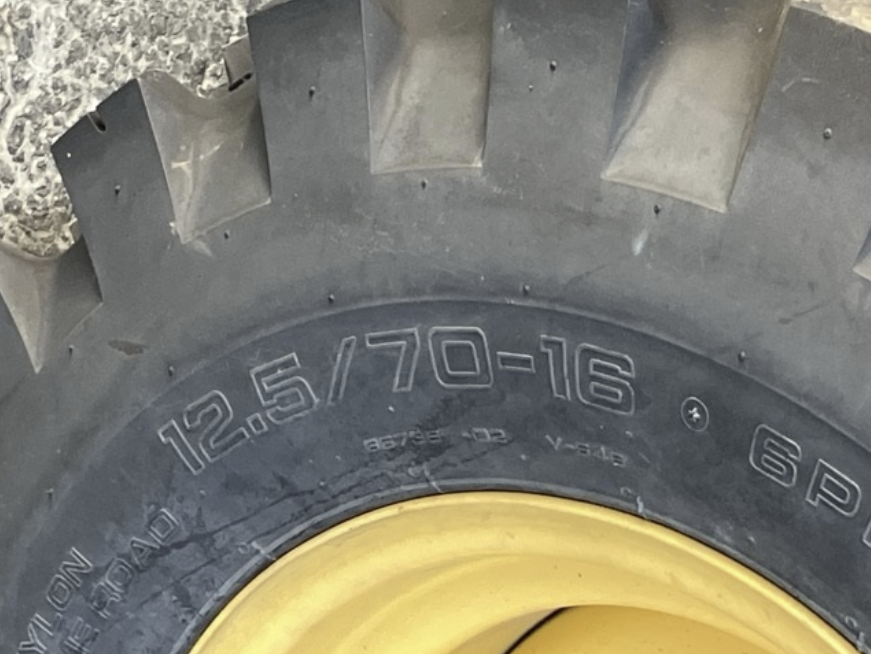 Close-up of a tire with the size and specifications marked on the sidewall, including 12.5/70-16.