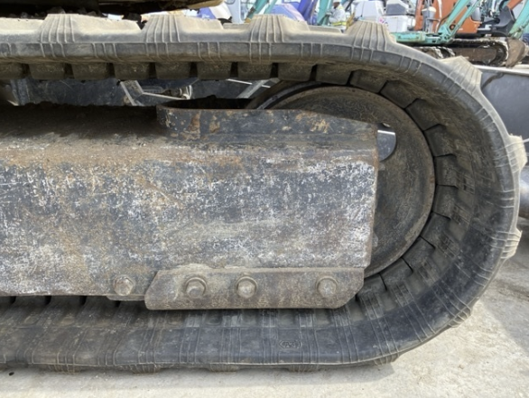 Close-up of a bulldozer's rubber track and undercarriage, showing dirt and wear.