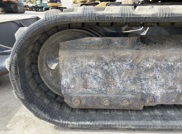 Close-up of a tracked construction vehicle's rubber track and metal undercarriage, showing signs of dirt and wear.