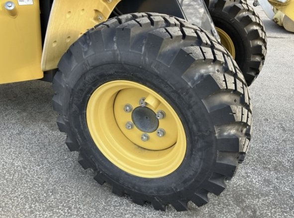 Close-up of a large yellow industrial or construction vehicle tire with deep treads, mounted on a yellow rim.