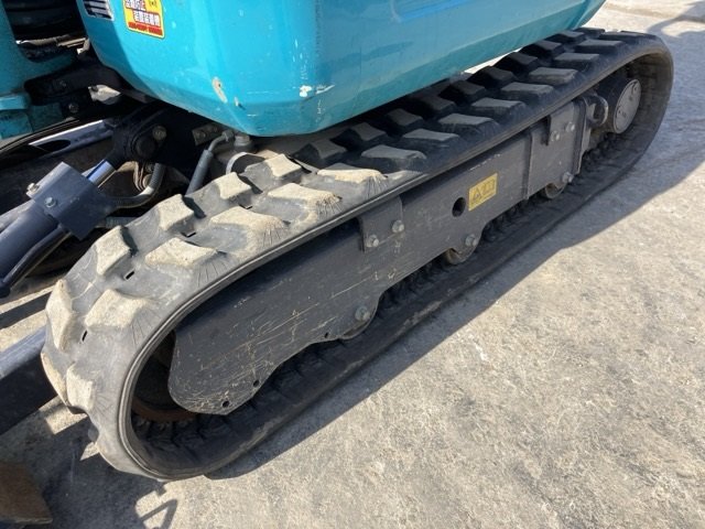 Front view of a construction vehicle's operator seat and controls, including steering levers and a large black seat, outdoors on a sunny day.
