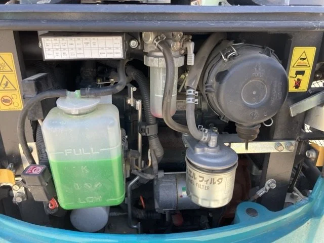 Close-up of a construction vehicle's rubber tracked undercarriage, showing the metal rollers and rubber track.