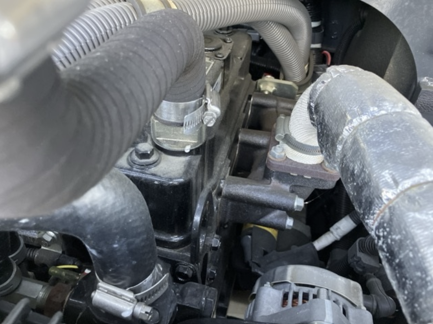 Close-up of a car engine showing hoses, clamps, and engine parts.
