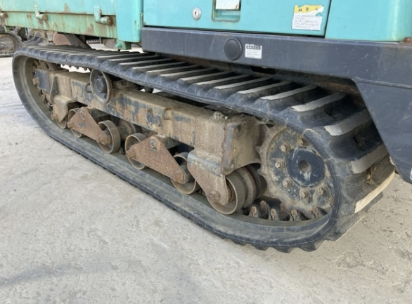 Close-up of a tracked construction vehicle's undercarriage showing dirt-covered metal tracks and rollers.