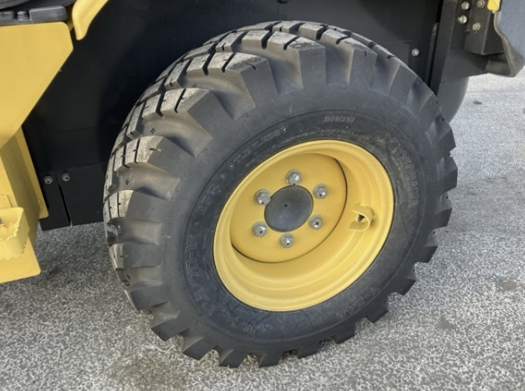 Close-up of a large off-road tire mounted on a yellow rim, attached to heavy construction equipment.