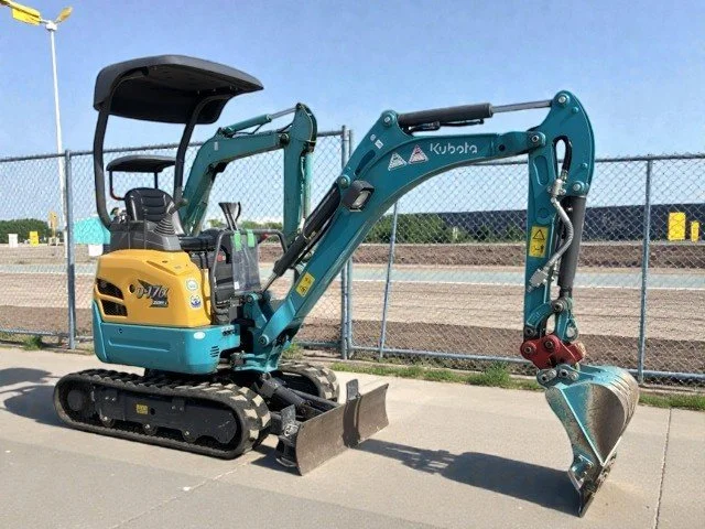 Close-up of a tracked construction vehicle's track and sprocket wheel, with dirt and dust on the metal parts.