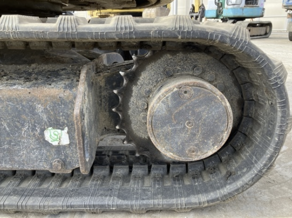 Close-up of a tracked vehicle's undercarriage, showing a sprocket wheel and rubber track.