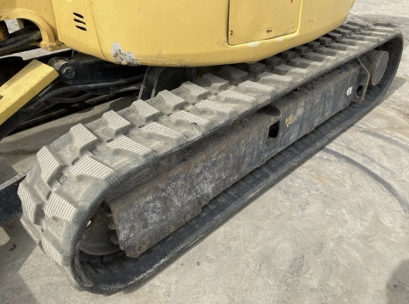 Close-up of a construction vehicle's rubber tracked undercarriage, showing the metal rollers and rubber track.