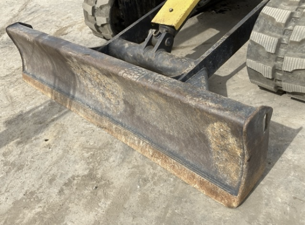 A large rusty bulldozer or skid-steer loader blade attachment on a concrete surface.
