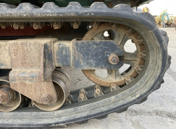 Close-up of a tractor track, showing metal and rubber components with dirt and wear.