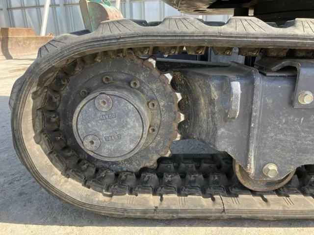 Close-up of a tracked construction vehicle's rubber track and metal undercarriage, showing signs of dirt and wear.