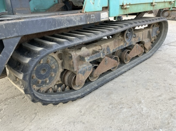 Close-up of a tracked construction vehicle's metal track and undercarriage components, showing rust and wear.