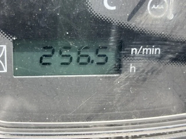 Construction vehicle seat with control levers and steering, outdoors in a yard.