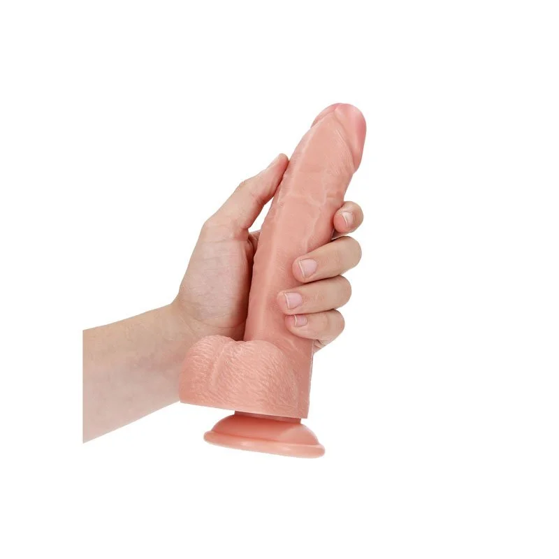 A hand holding a realistic flesh-colored dildo with a suction cup base.