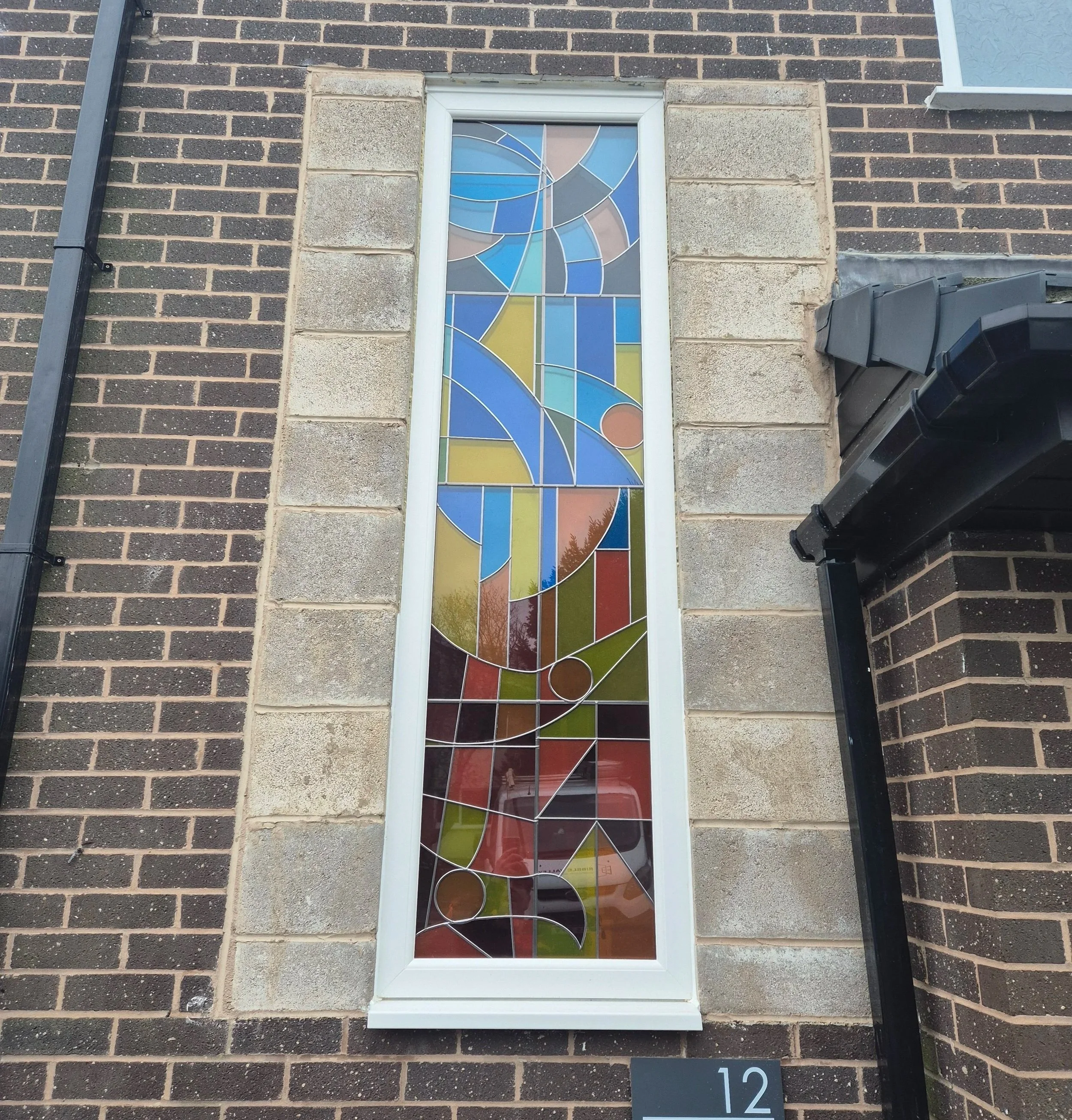 Bespoke colourful stained glass window with abstract geometric design. The customer wanted to add personality to their stairwell, whilst maintaining privacy and maximising the light into their home.
