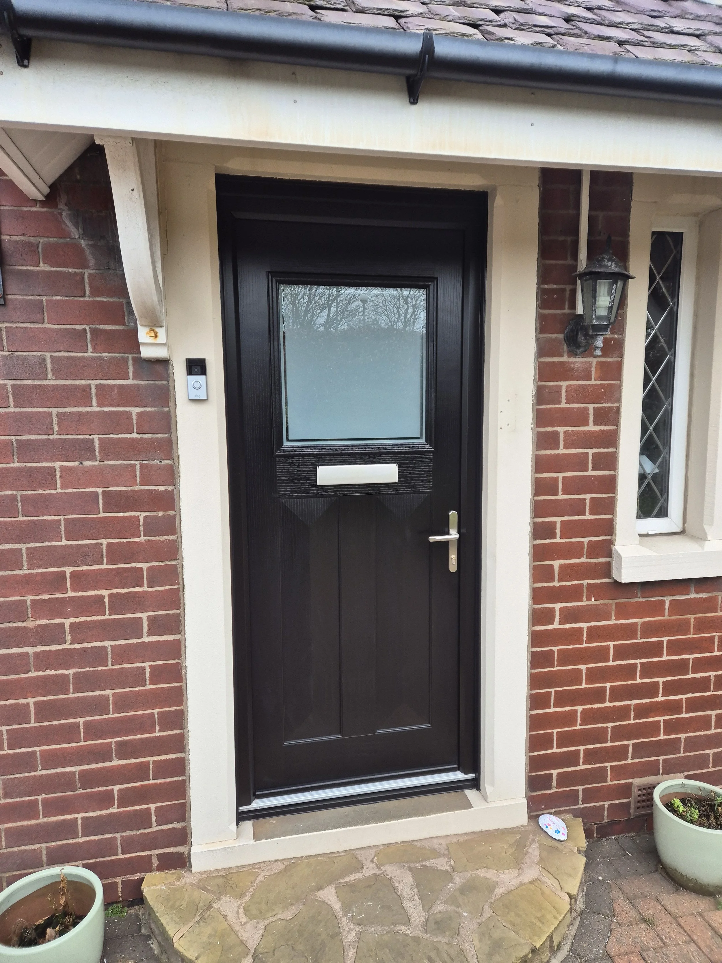 Traditional style black composite front door, set in a crisp white frame. The door features satin glass which maximises privacy whilst allowing natural light into the home.