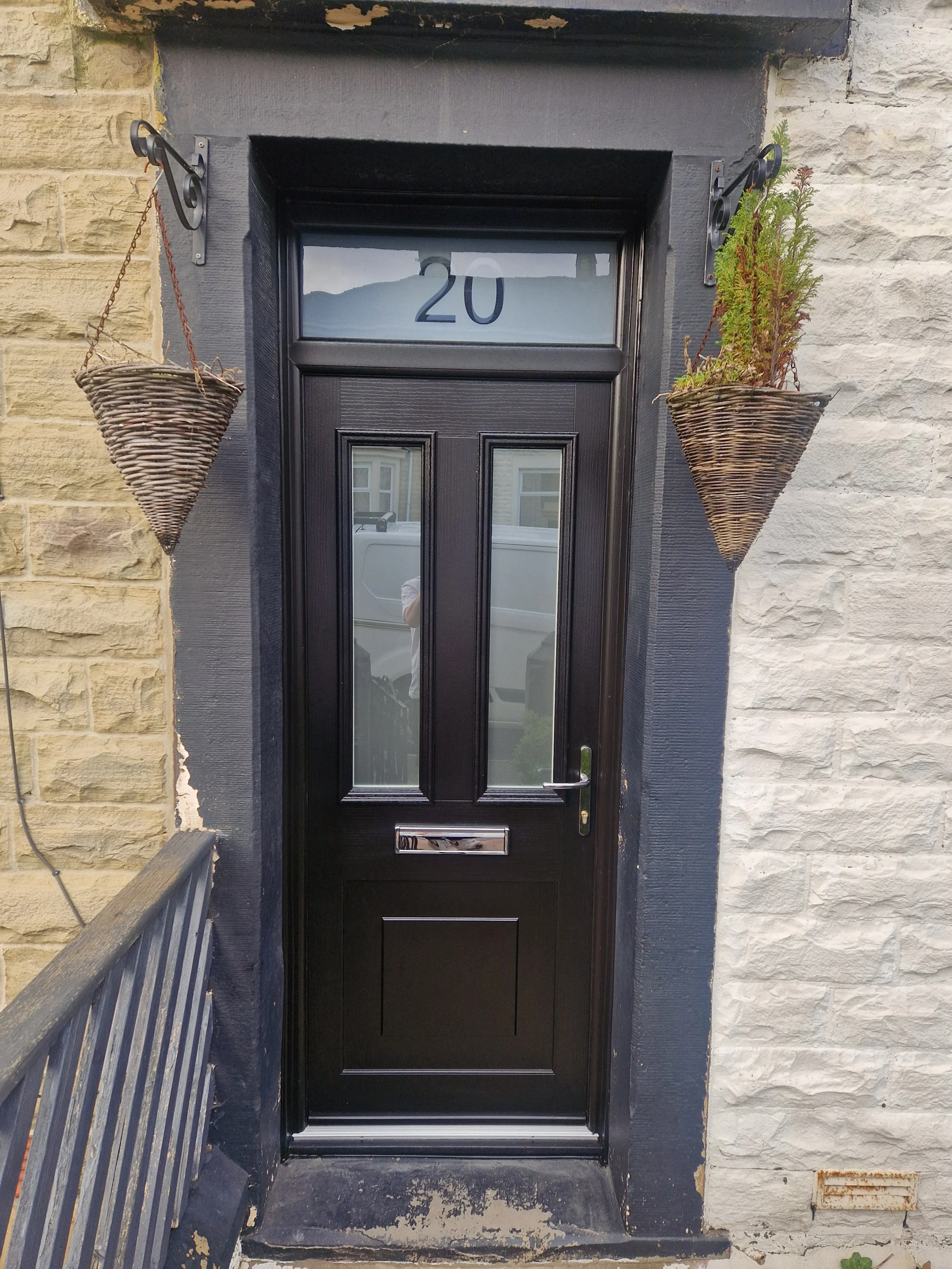 Black composite front door featuring satin glass panels, matching black outer frame, and a bespoke overhead fanlight with the house number etched into satin glass.