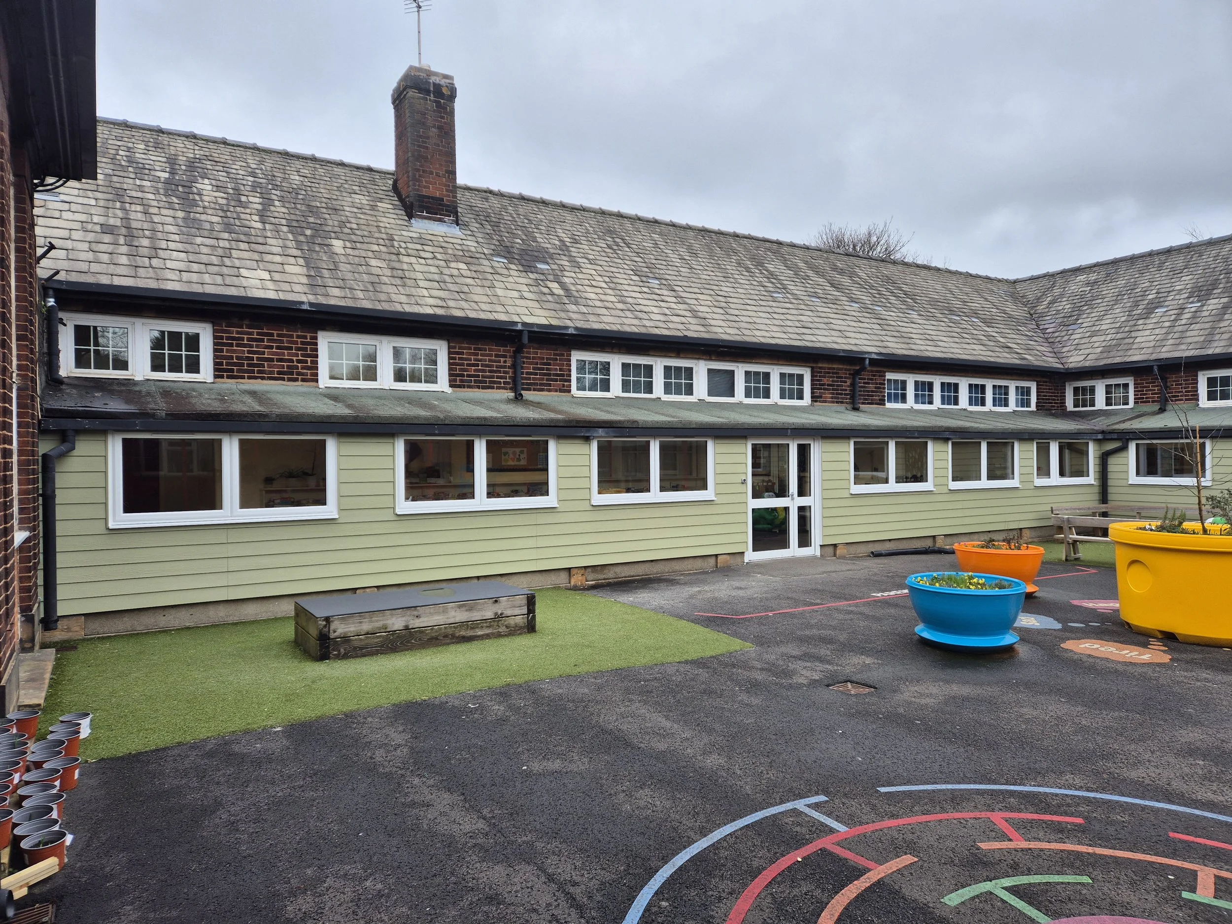 Commercial uPVC window replacement and sage green cladding installation at a local school. The energy-efficient white PVC frames completely replace the building's outdated windows, paired with durable ground-floor cladding to modernise the exterior a