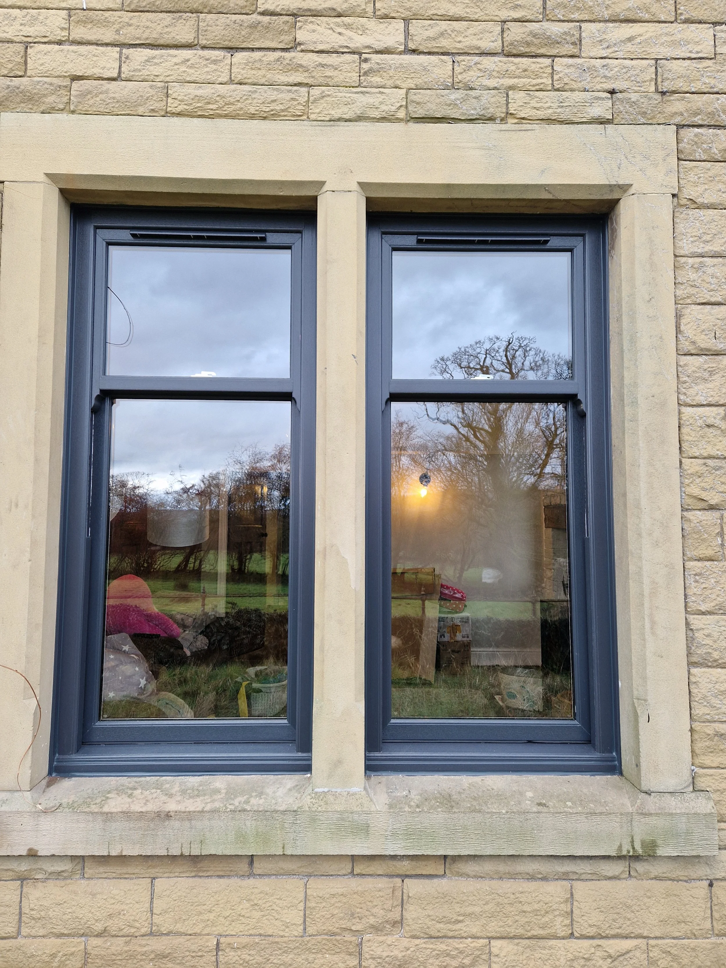 Pair of Anthracite Grey PVC sliding sash windows featuring a modern dark profile on a classic heritage design. These vertical sliders seamlessly combine traditional architectural charm on a period property.