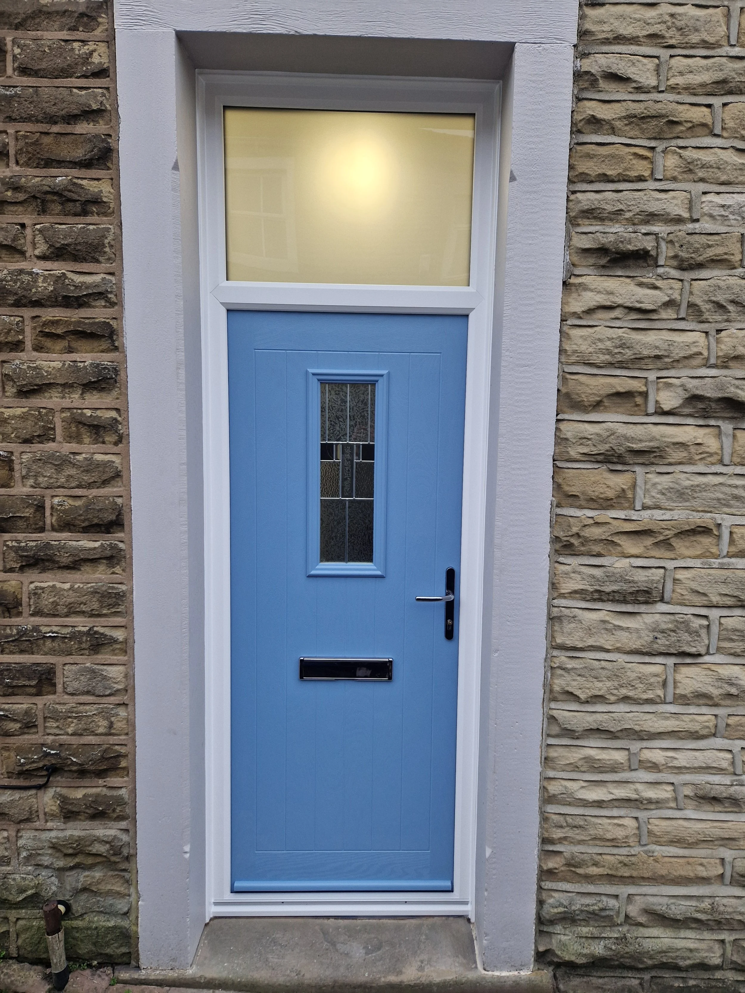 Blue composite front door  with decorative glass, in a crisp white frame. Large fan light above fitted with satin glass.