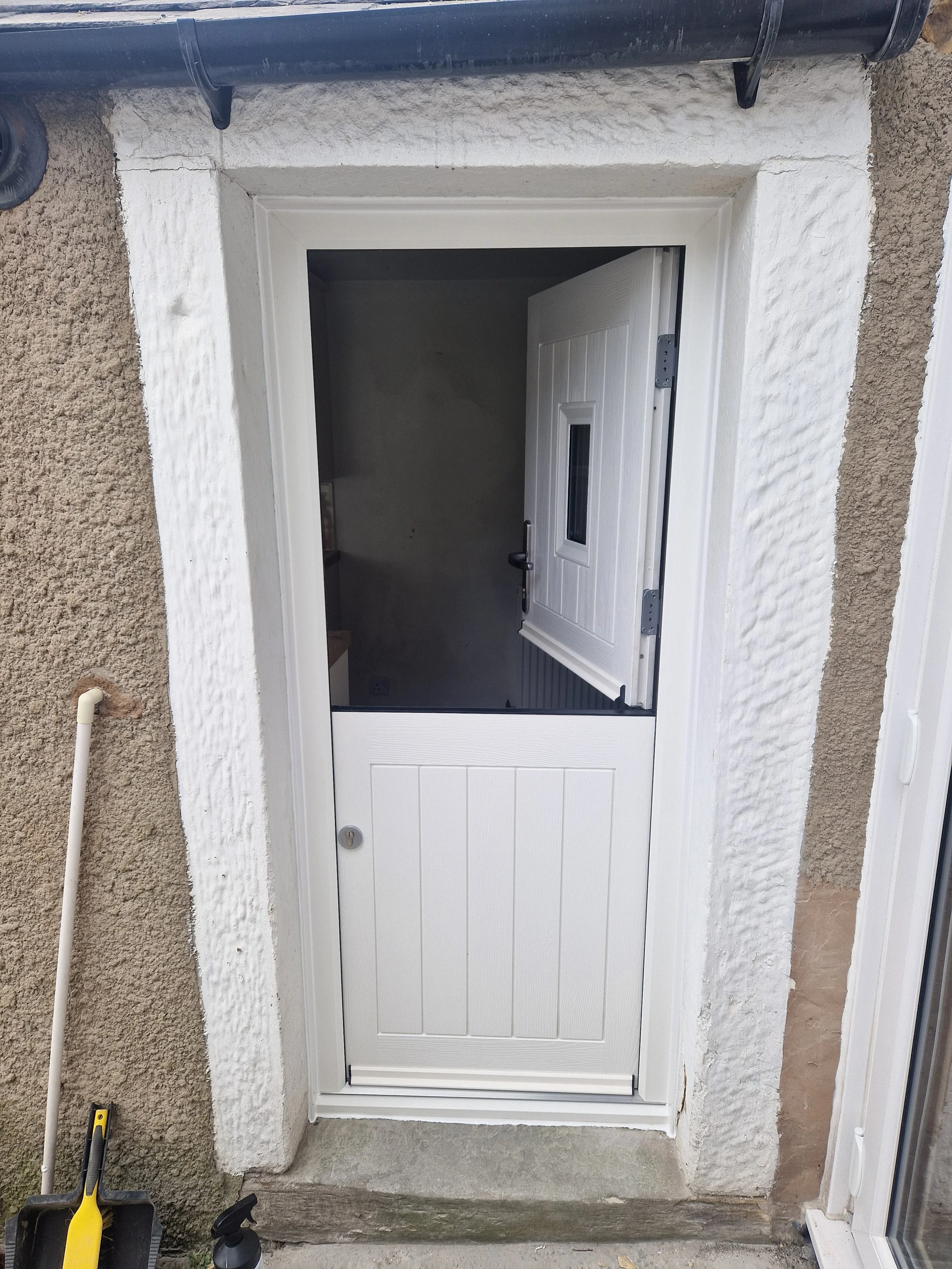 White composite stable door fitted as a high-security back door upgrade for a character cottage. The classic split-door design allows the top half to open independently for ventilation and views while keeping the bottom half safely secure.