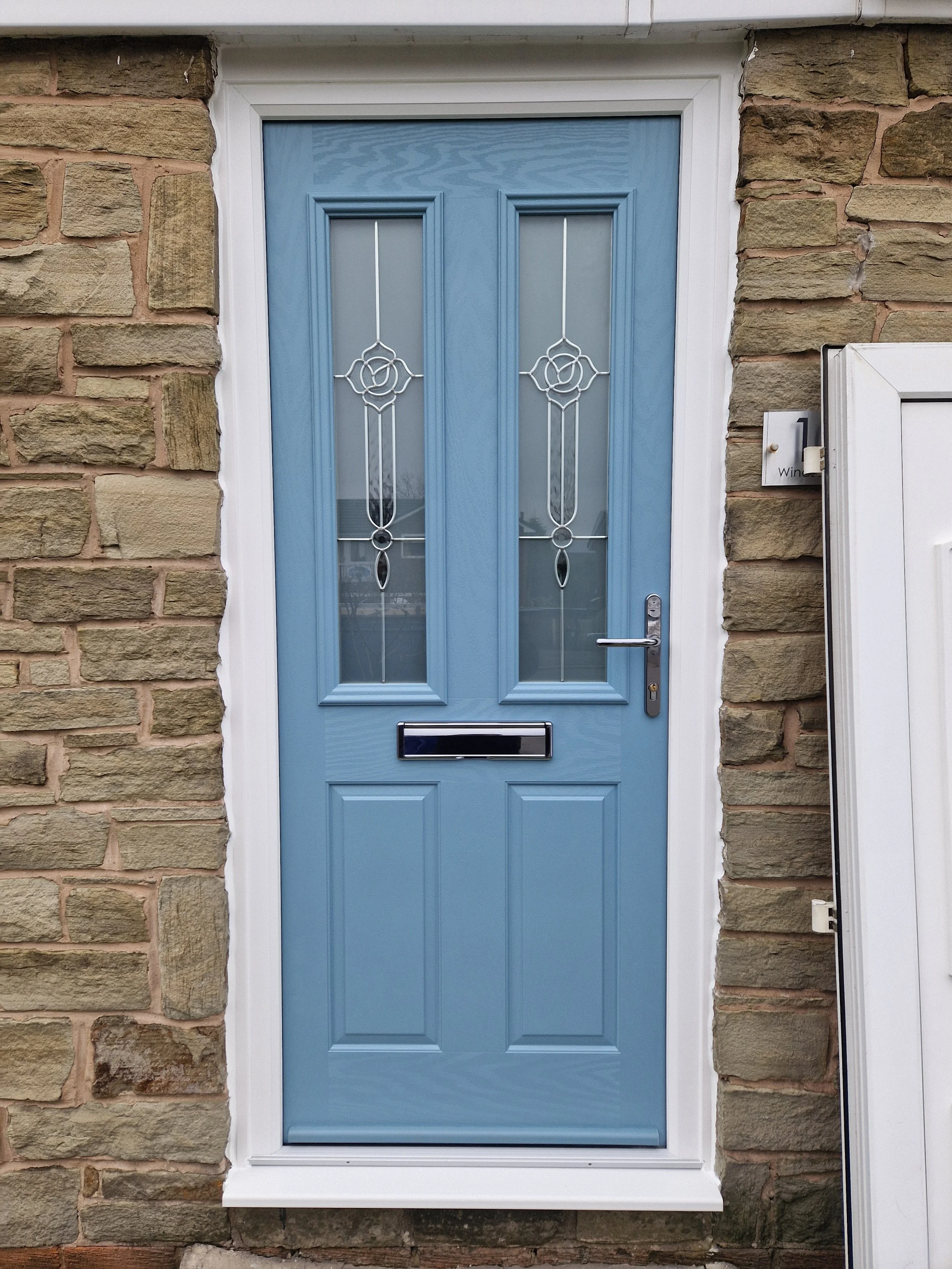 Light blue composite front entrance door featuring decorative glass privacy panels and a crisp white frame. This low-maintenance upgrade adds instant kerb appeal and exceptional thermal efficiency.