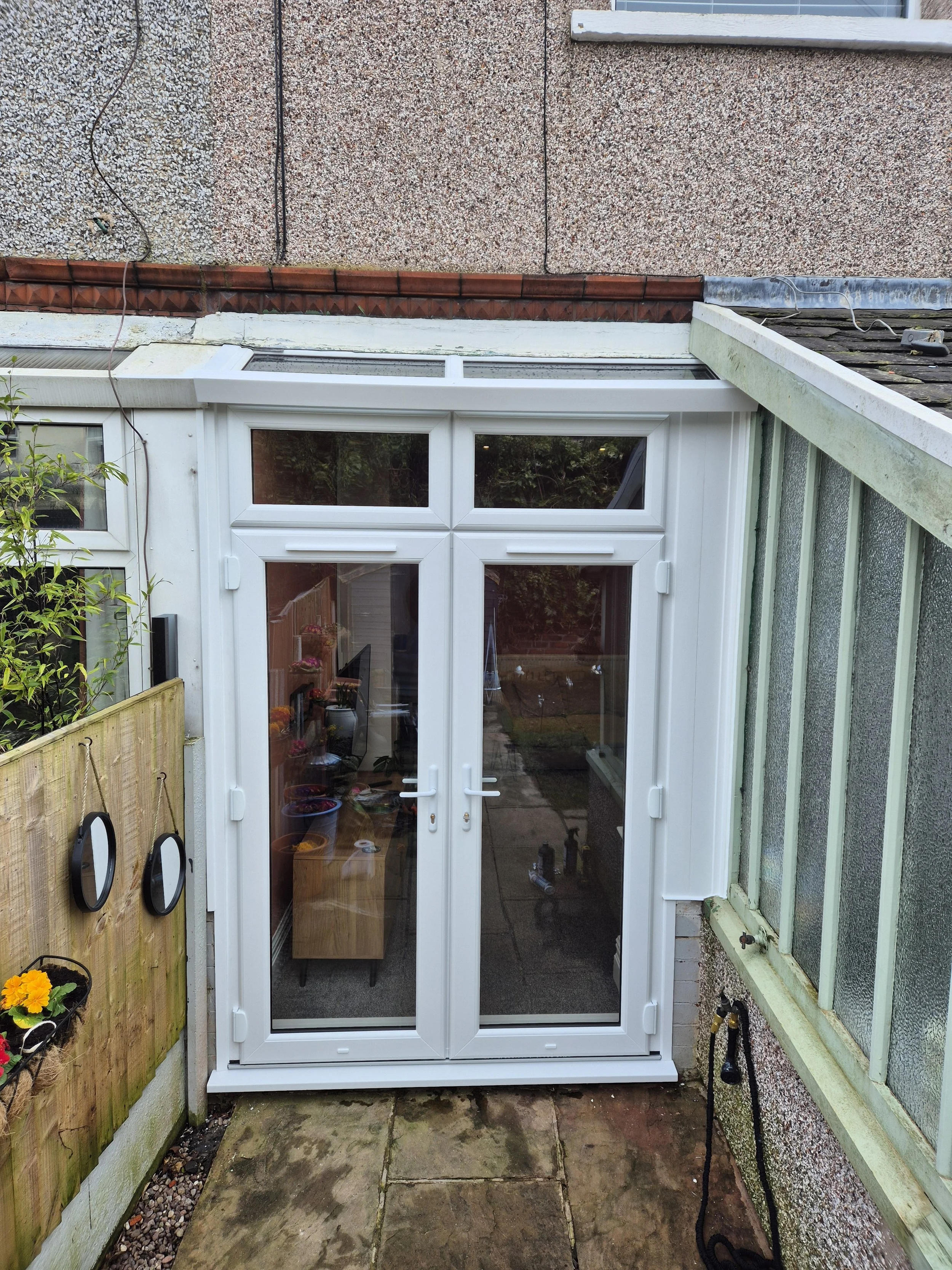 White PVC French doors precision-fitted into a newly enlarged wall opening, replacing a standard rear window. This creates a seamless transition from the home directly into the back yard, maximising natural light and accessibility.