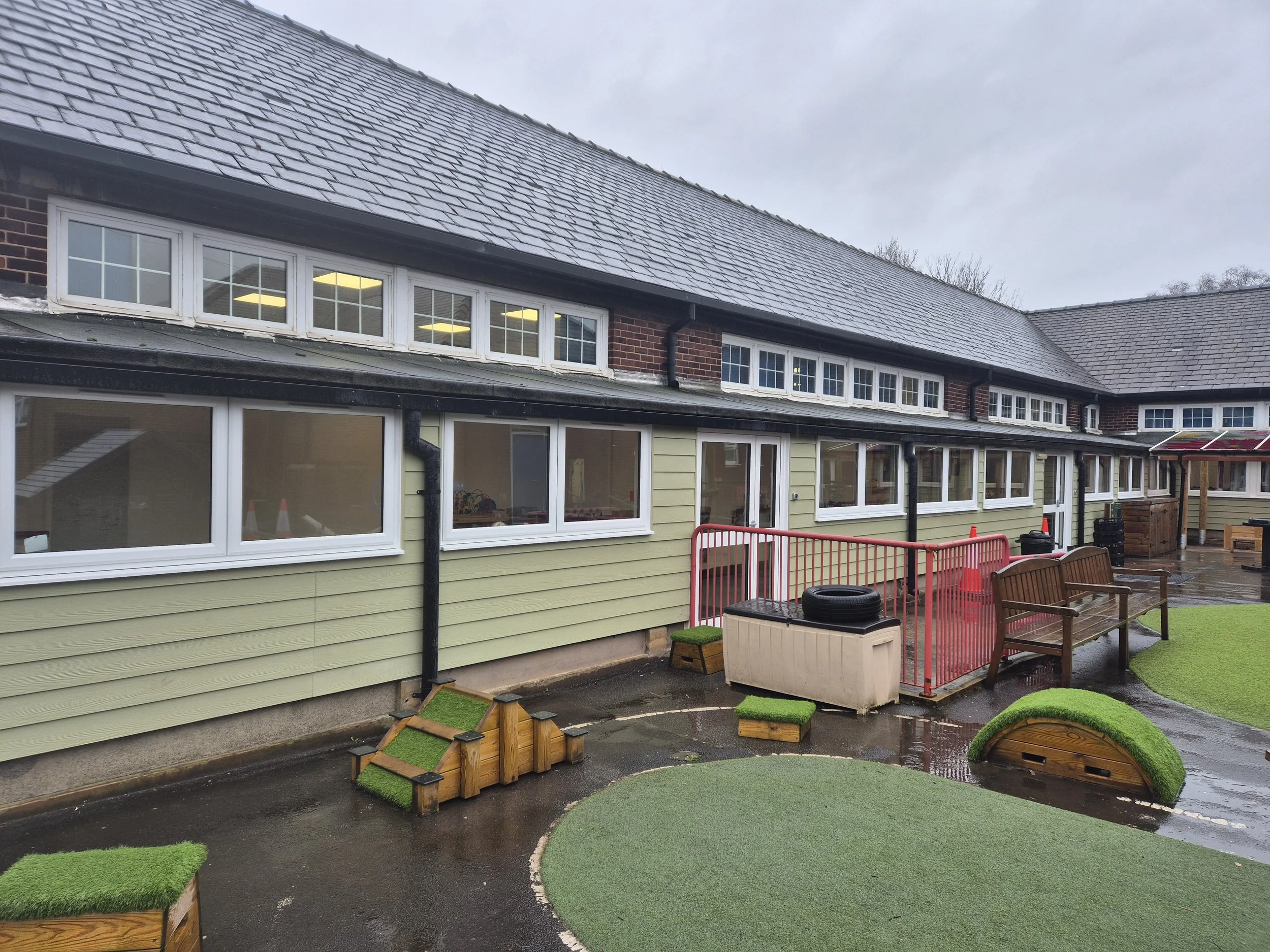 Commercial uPVC window replacement and sage green cladding installation at a local school. The energy-efficient white PVC frames completely replace the building's outdated windows, paired with durable ground-floor cladding to modernise the exterior a