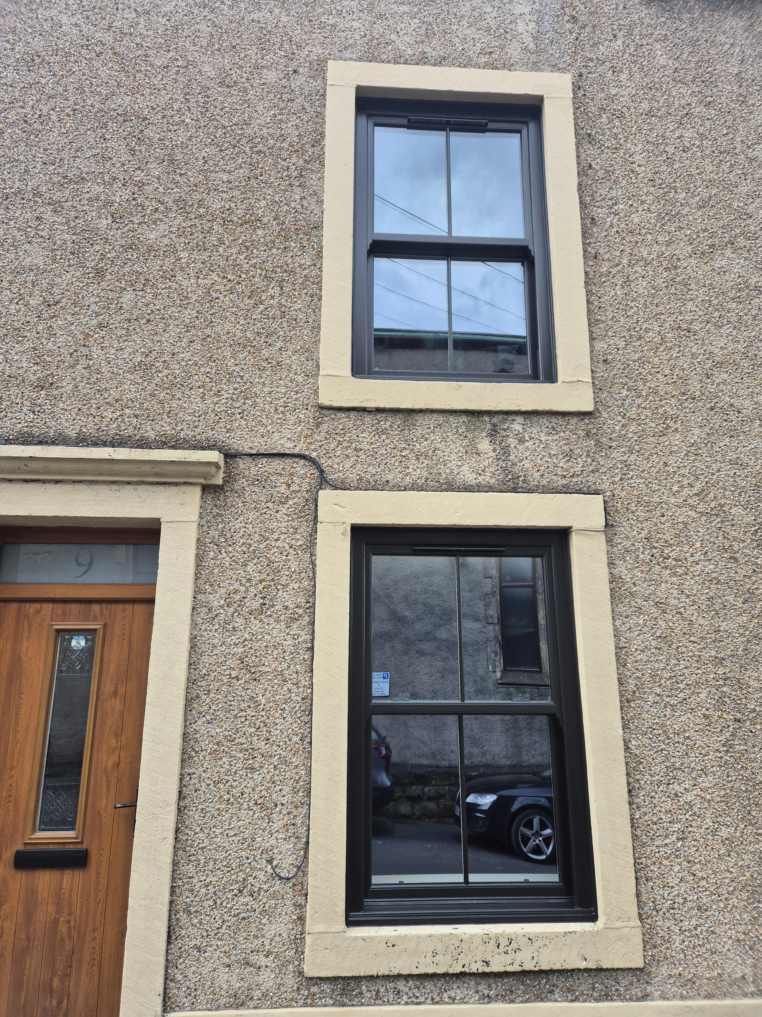 Black PVC sliding sash windows. The windows are designed in a traditional style without the maintenance required for traditional wooden sliding windows. 