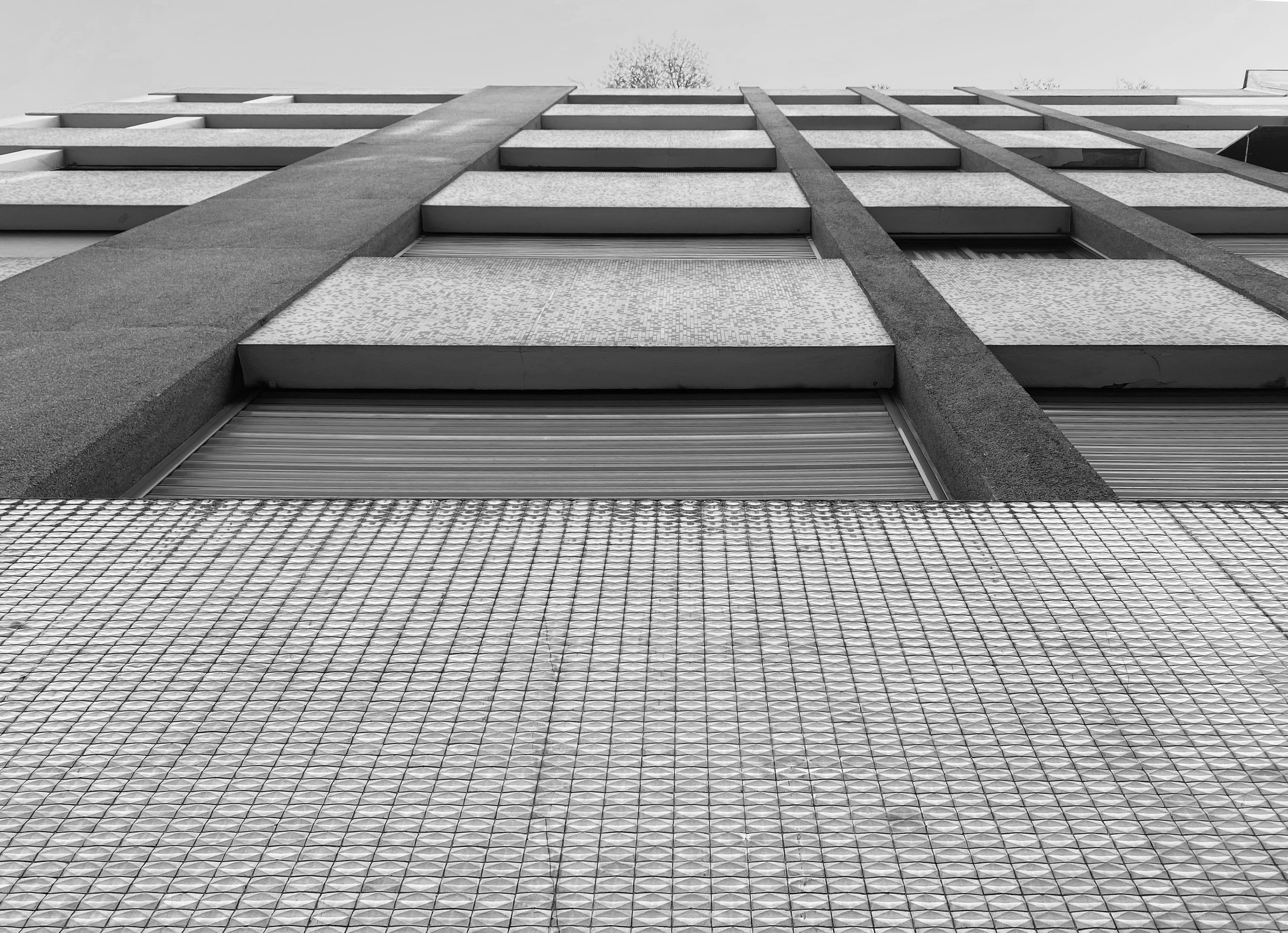 Vue en contre-plongée d'un immeuble moderne avec fenêtres, en noir et blanc.
