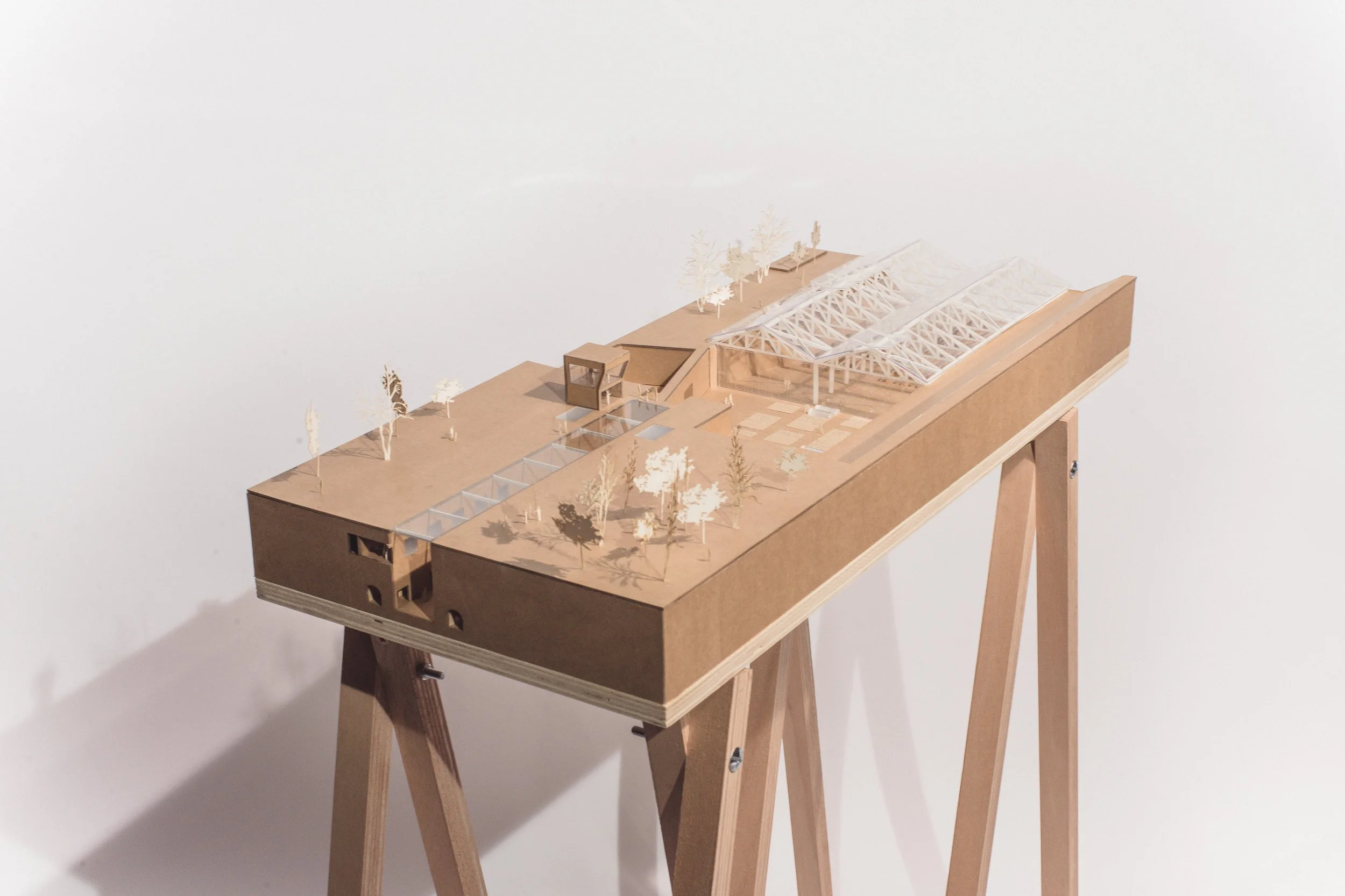 Maquette en bois d'un bâtiment architectural avec structures en verre et plancher extérieur, placé sur un support en bois