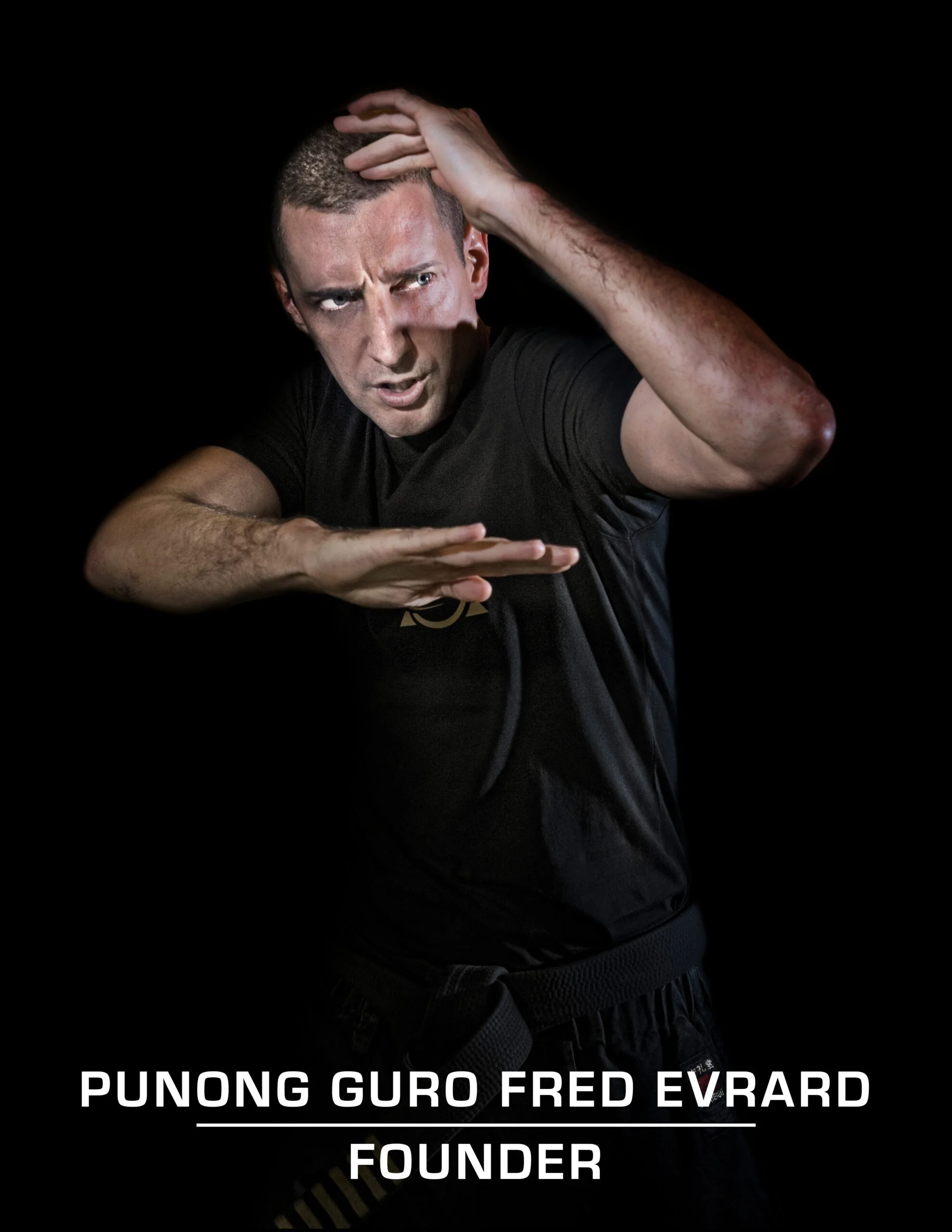 Young man with short hair making a martial arts pose on a black background, wearing a black martial arts uniform, and displaying intense focus. Text at the bottom reads 'Punong Guro Fred Evrard Founder'.