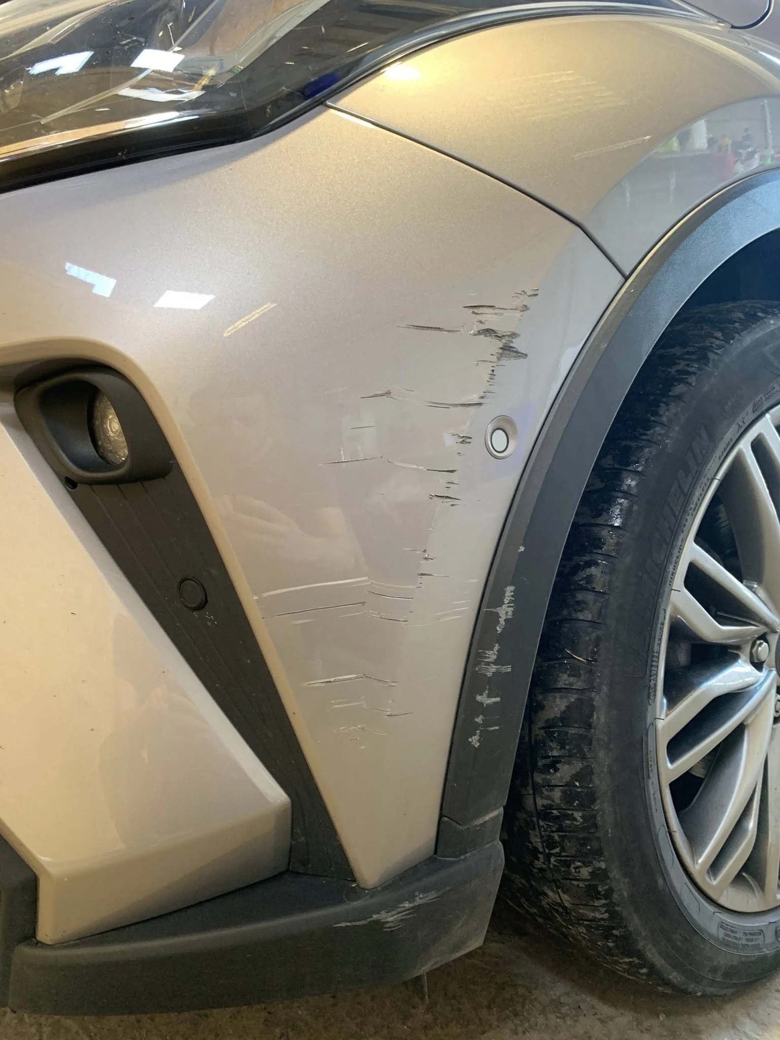 Car with scratches and dents on front right fender and bumper.