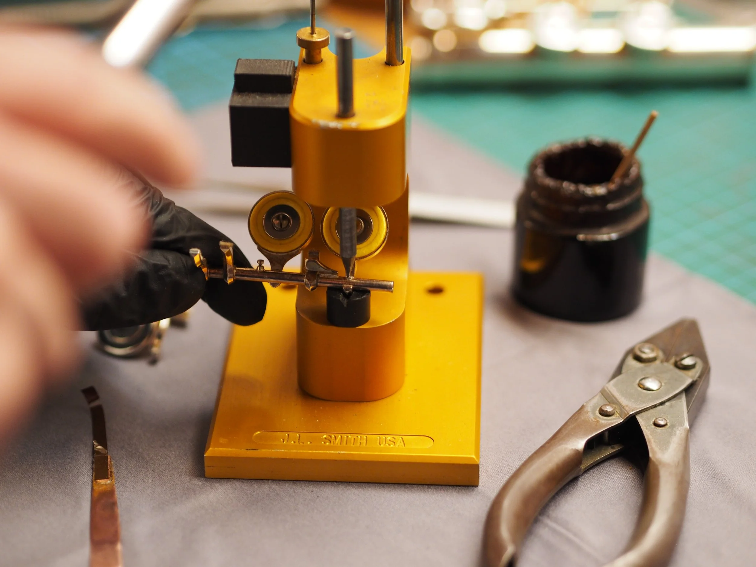 Werkzeug zur Drahtbearbeitung auf einem grauen Tisch mit einem Metallarmreif