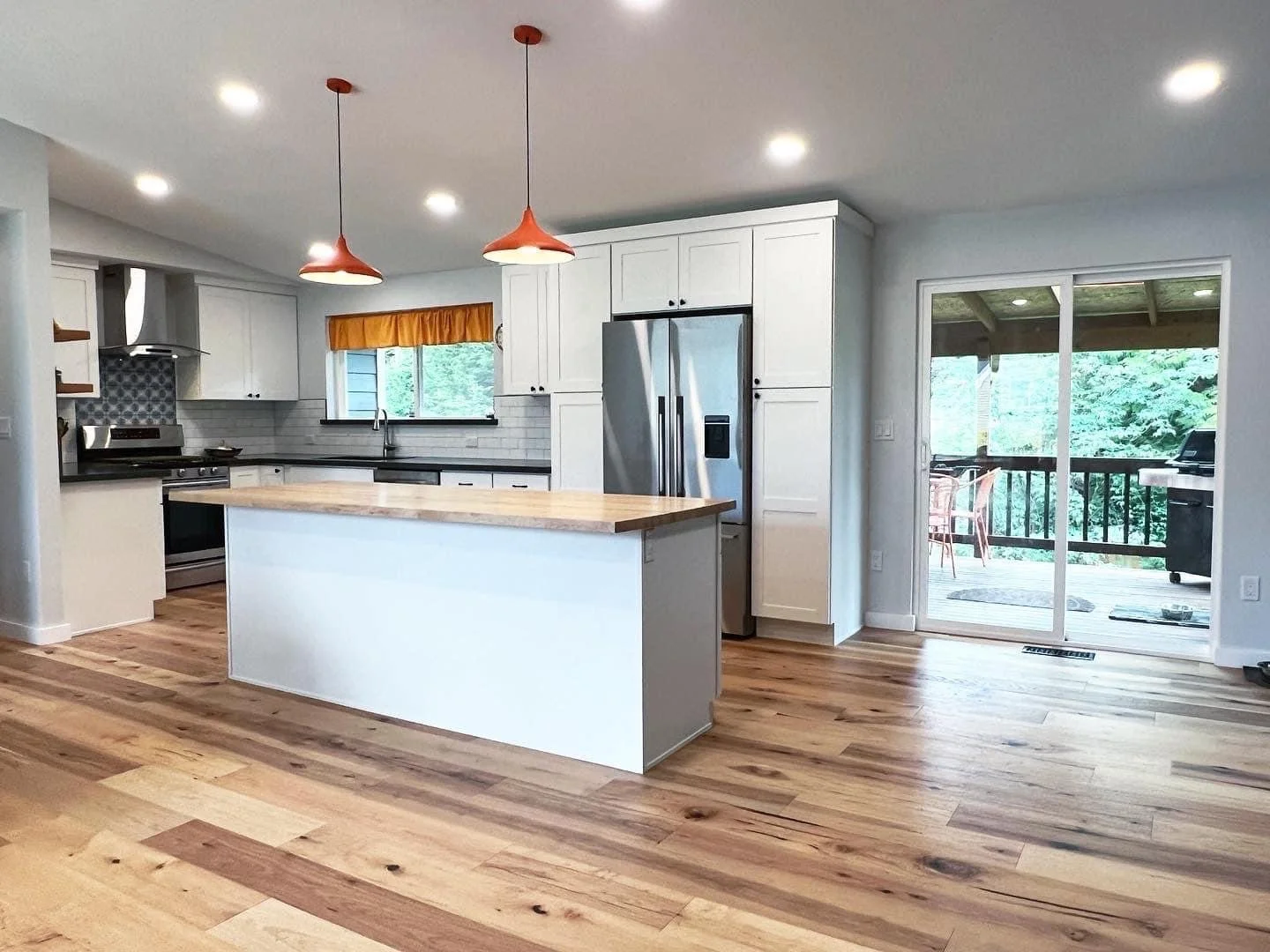 Bothell kitchen remodel with intentional and well-placed splashes of color. We added the butcher block island top, moved the backdoor, and added custom tile behind the range. 
