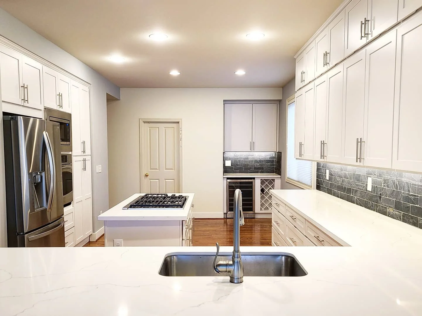 Sammamish kitchen remodel got a beautiful refresh with the addition of the cabinets against the ceiling, a wine fridge and wine rack, and under-cabinet lighting. The slate backsplash really makes the kitchen pop!
