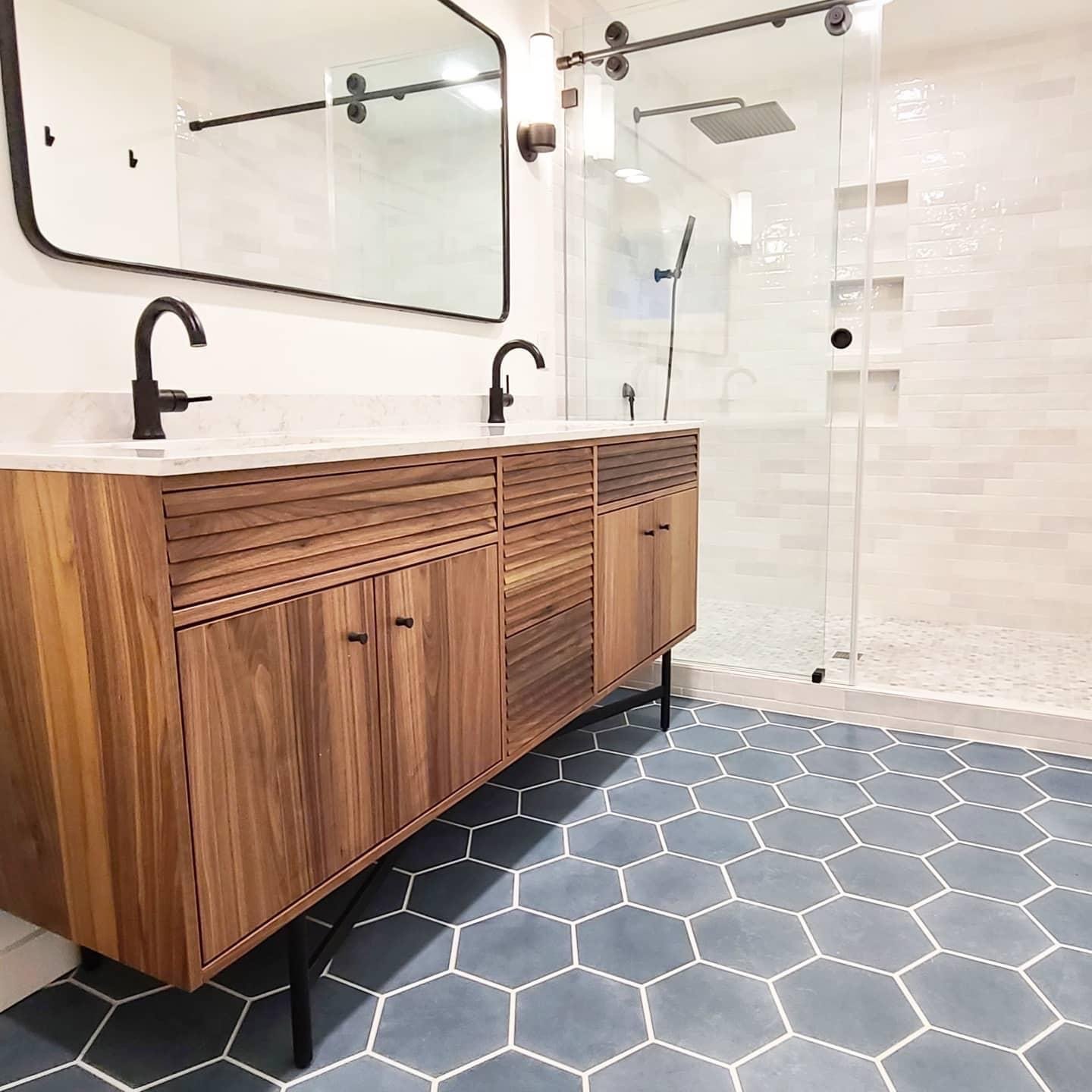 Mid-century main bathroom remodel with dark hexagonal floor tile, bright shower tile, and elegant black hardware finishes.