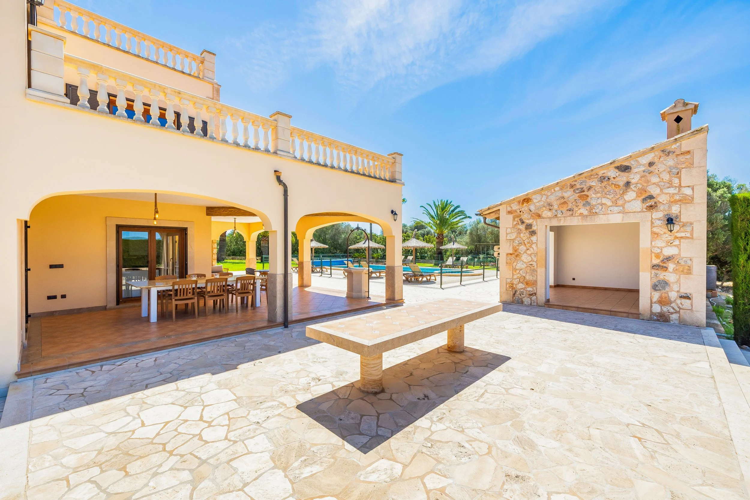 Casa de verano con balcón, patio y piscina, en un día soleado.