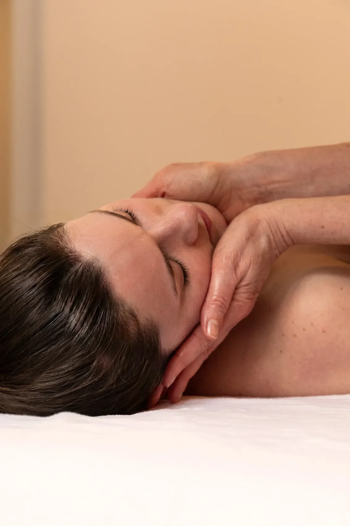 Une femme reçoit un massage du visage dans un cadre paisible.