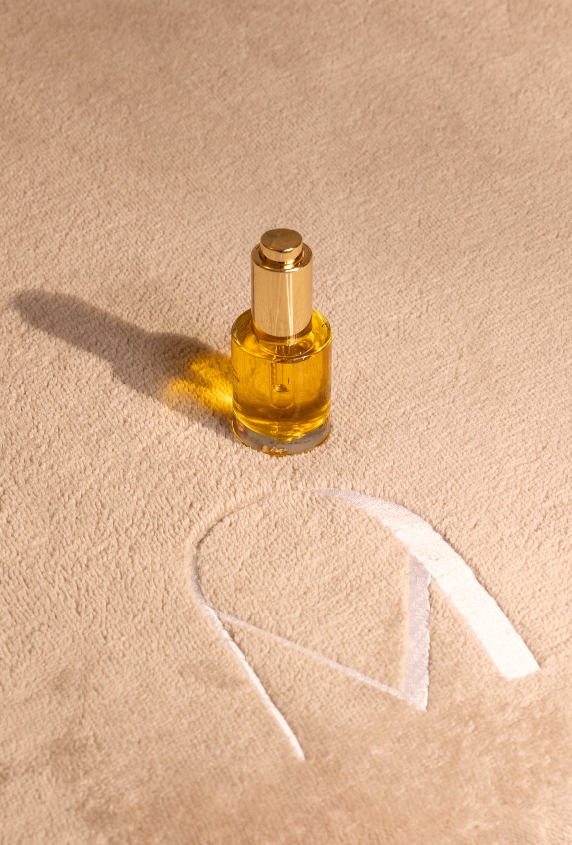 Un flacon de parfum doré sur fond beige
