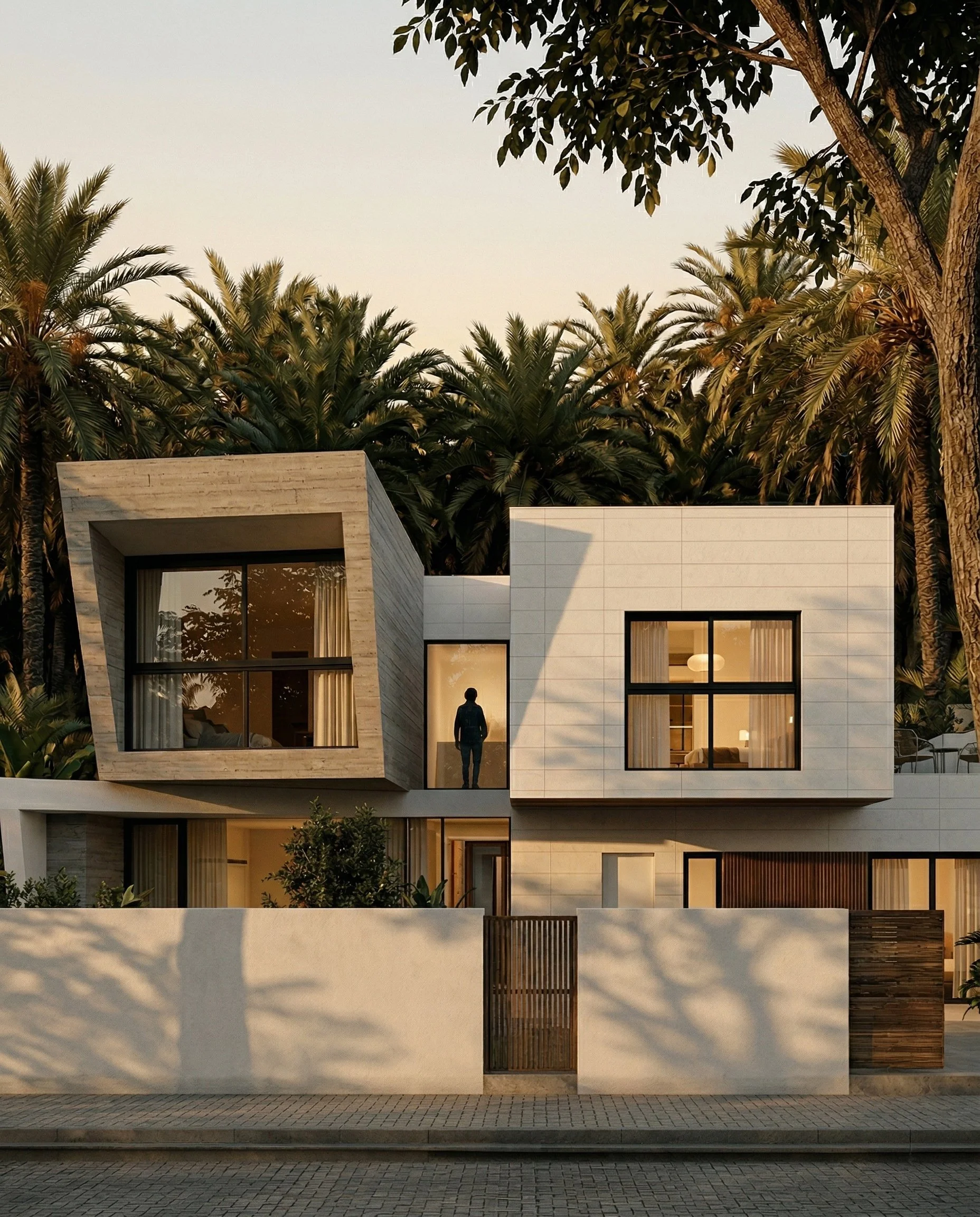 Edificio de diseño modular construido en estructura de madera de dos pisos con diseño minimalista, paredes blancas y grandes ventanas, rodeada de árboles y vegetación, durante el atardecer.