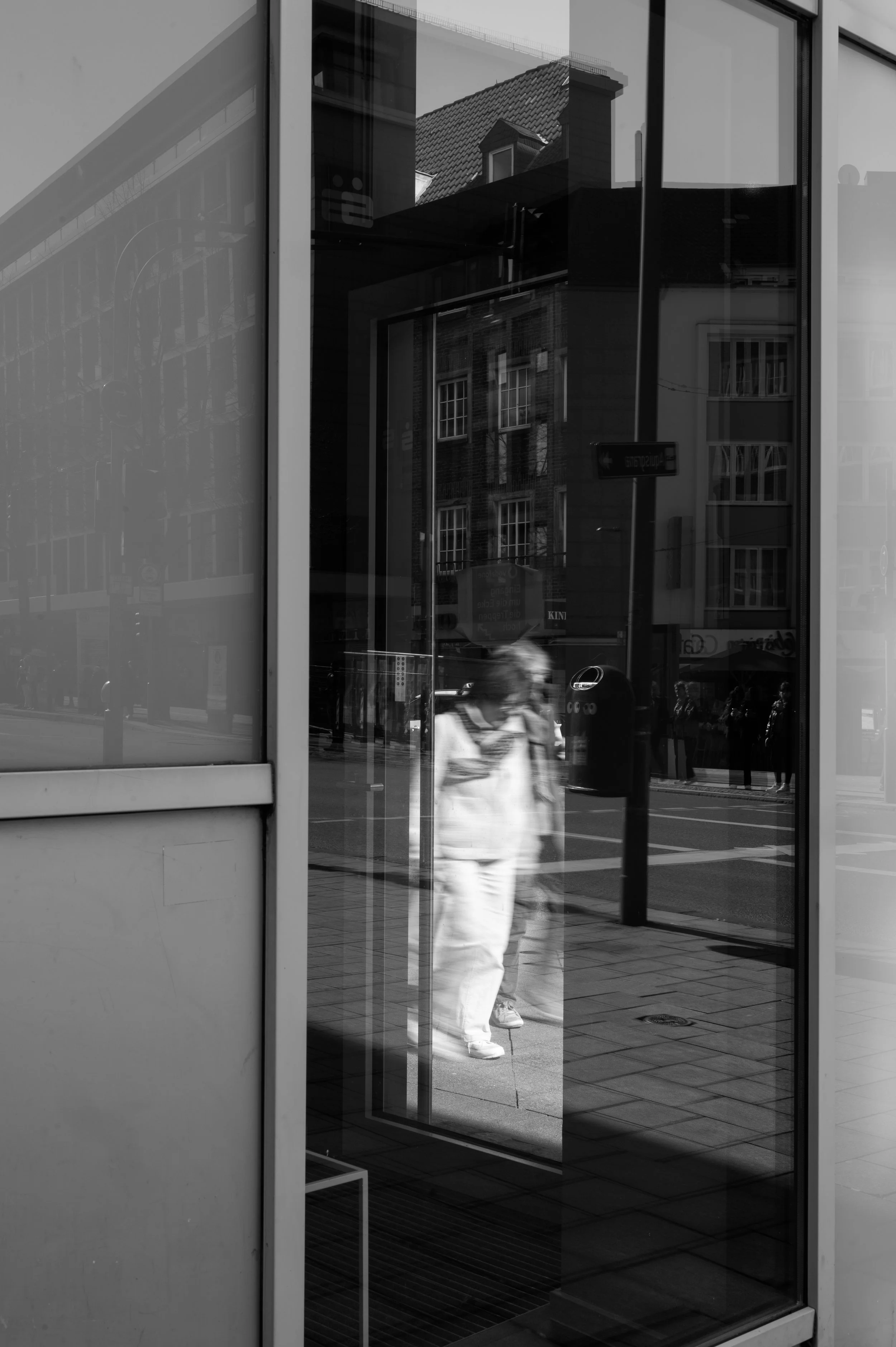 Through a window and an open door on the otherside, two older lady walking by, slightly blured as time is walking by.