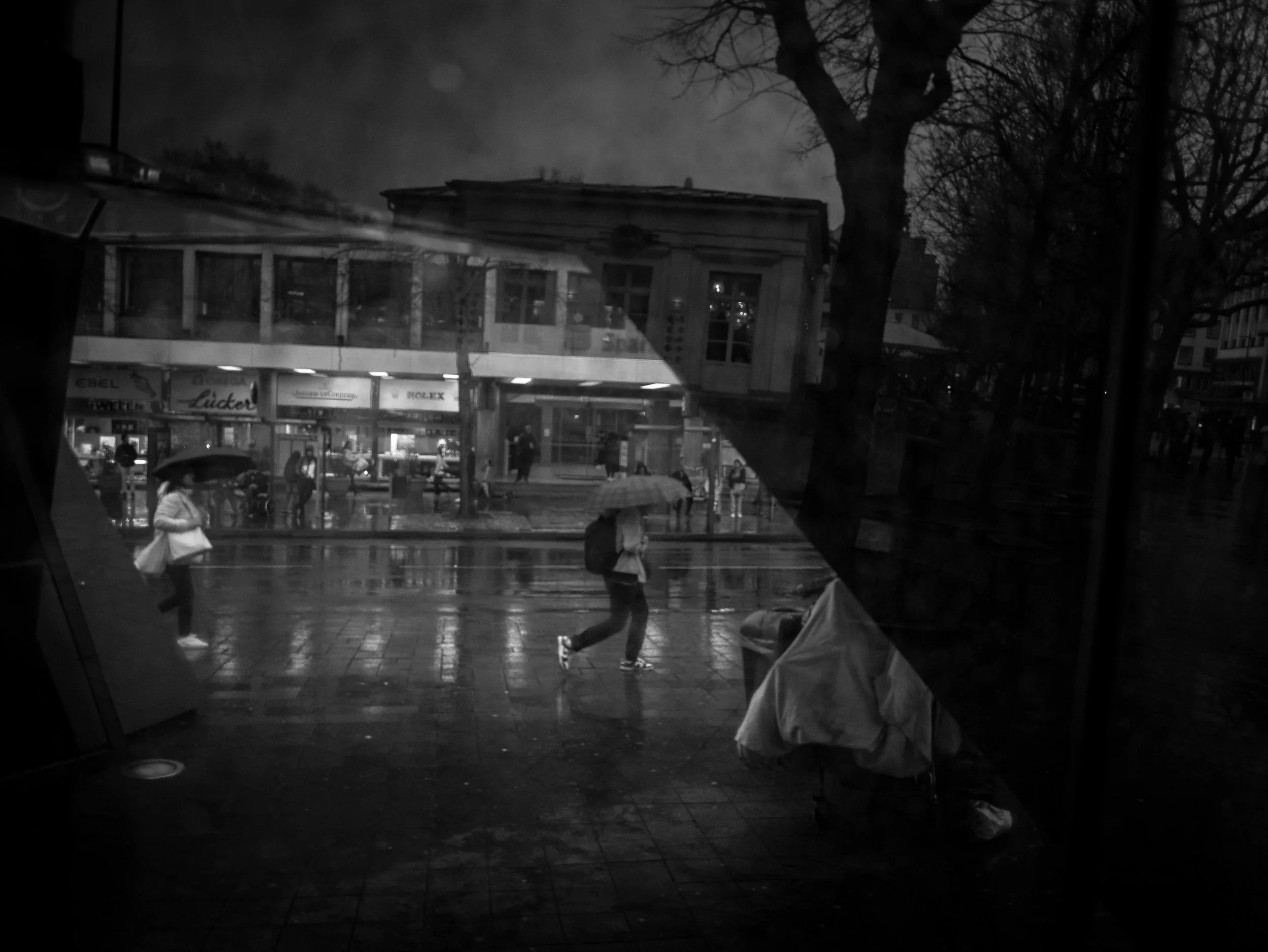 Relfections everywhere and the people in the scene are walking buy under their umbrella's
