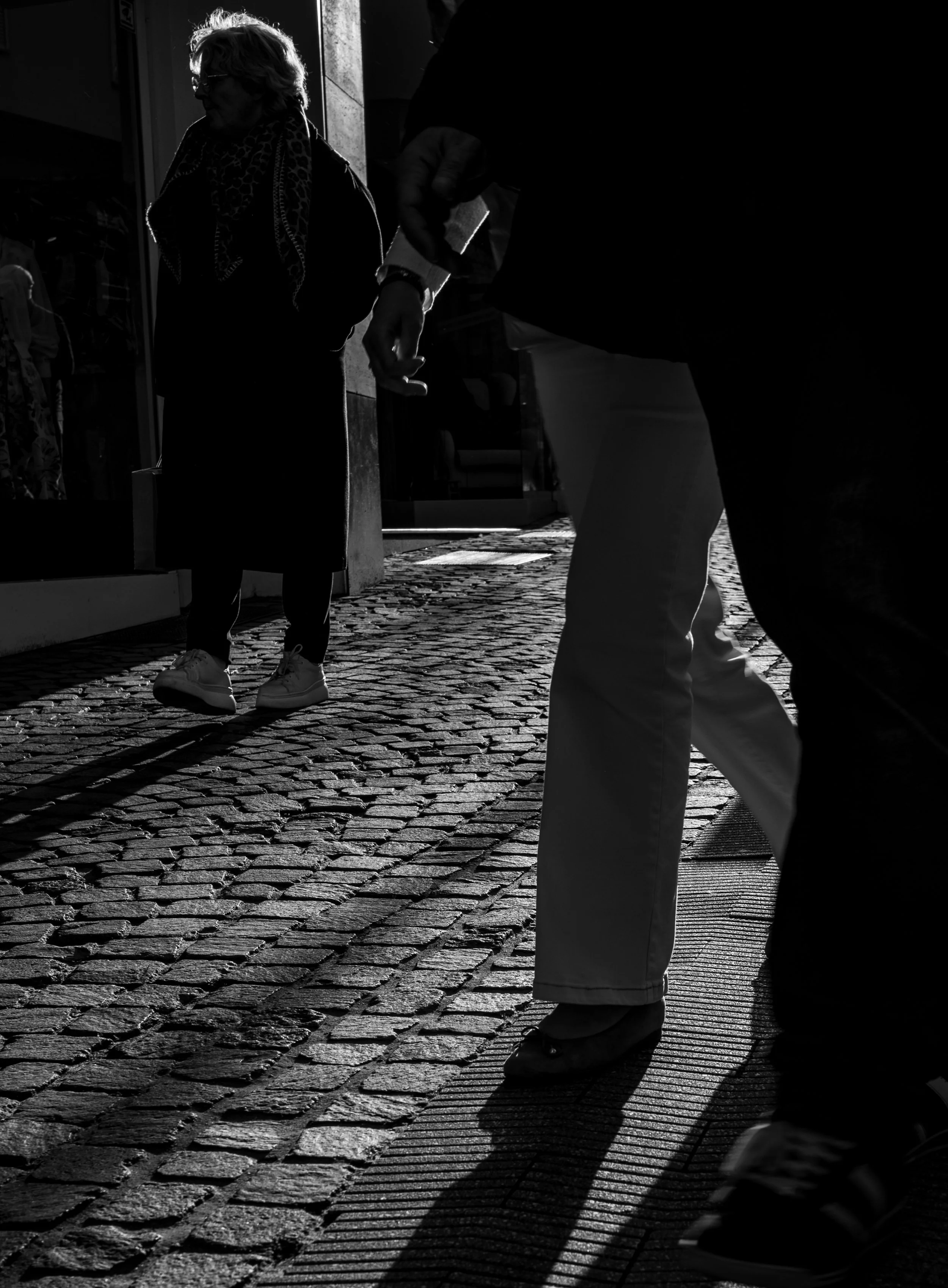 Walking the old streets. Backlit people walking the shopping streets of Aachen. Throwing long shadows.