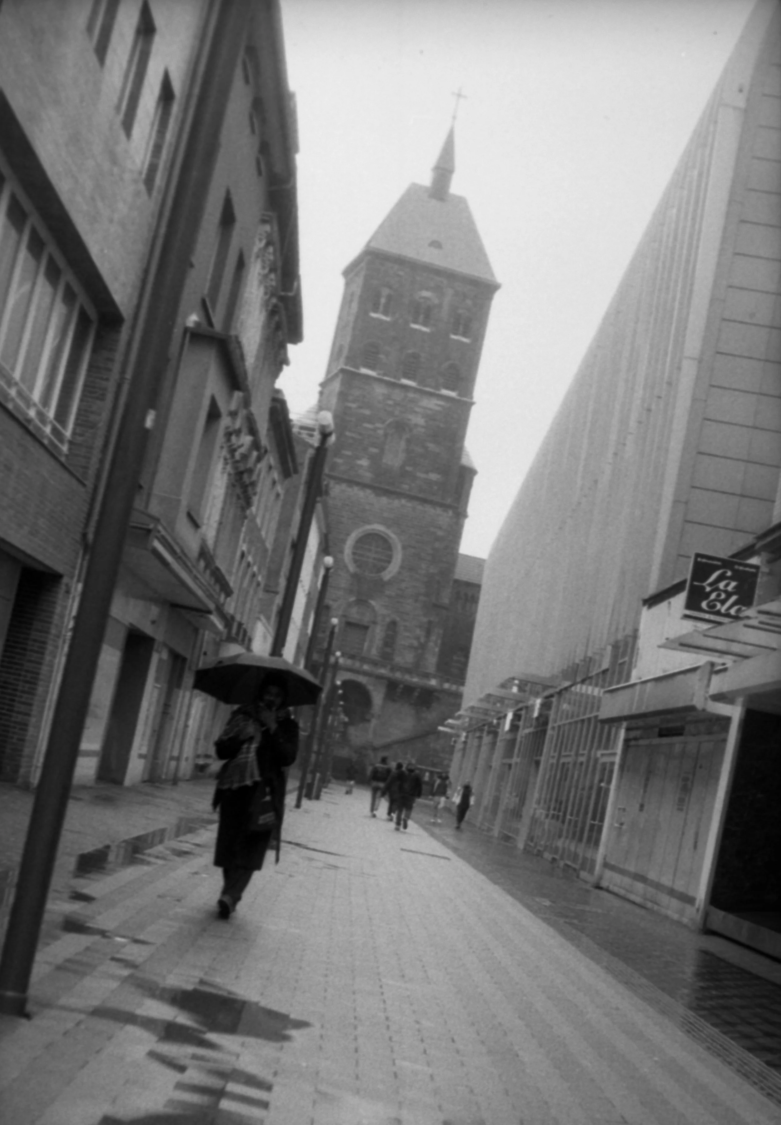 Analog Street picture of a woman with an umbrella on a rainy day in the city.
