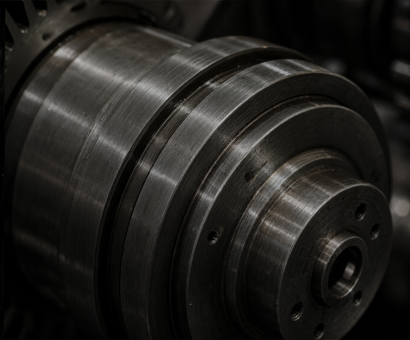 Close-up of a large metal industrial machine part with a smooth, shiny, and machined surface, featuring concentric rings and small holes.