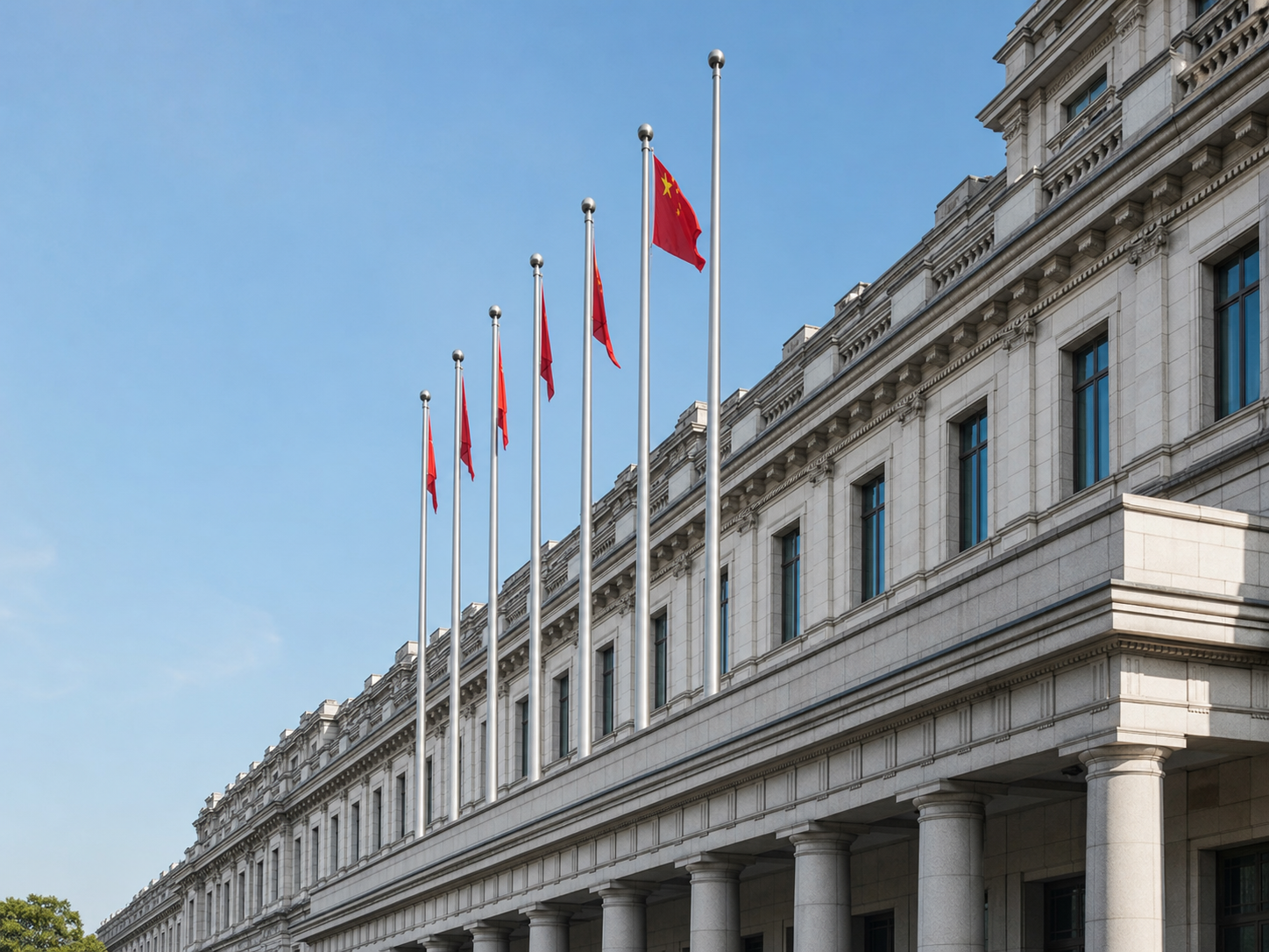 A government building with classical architecture and tall flagpoles flying the flag of China.