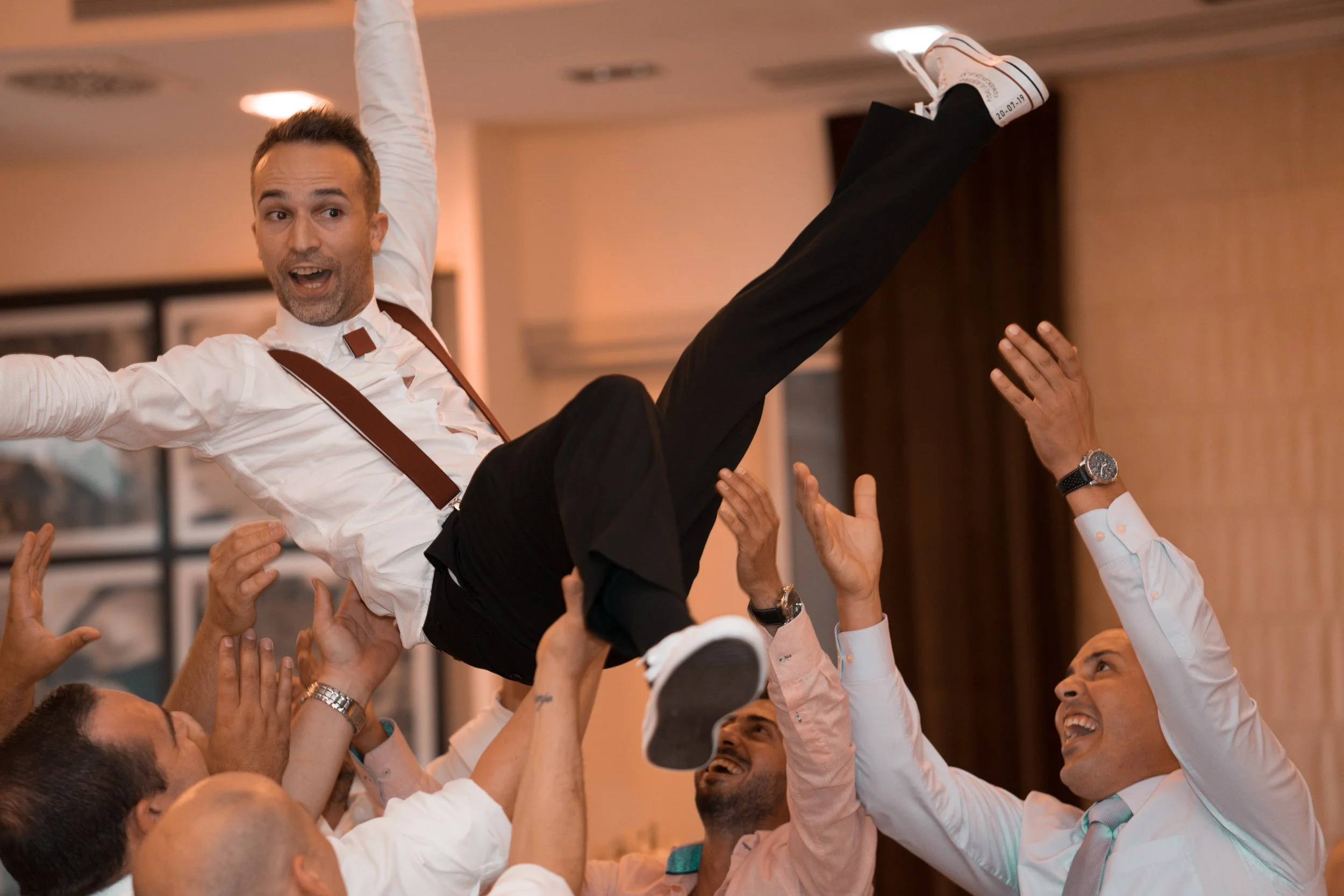 Un grupo de hombres levantando a un hombre en una celebración o ceremonia, todos parecen felices y emocionados.